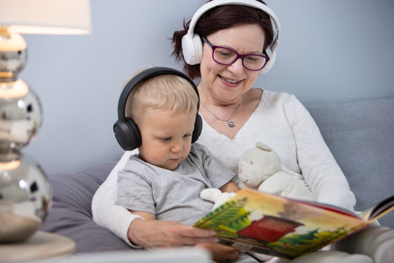 En person sitter i en stol och lyssnar på en talbok med en barn.